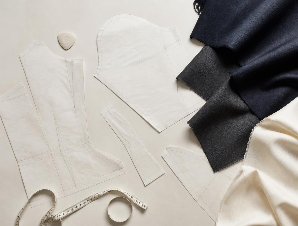 Garment pattern pieces, fabric swatches and a measuring tape laid out flat
