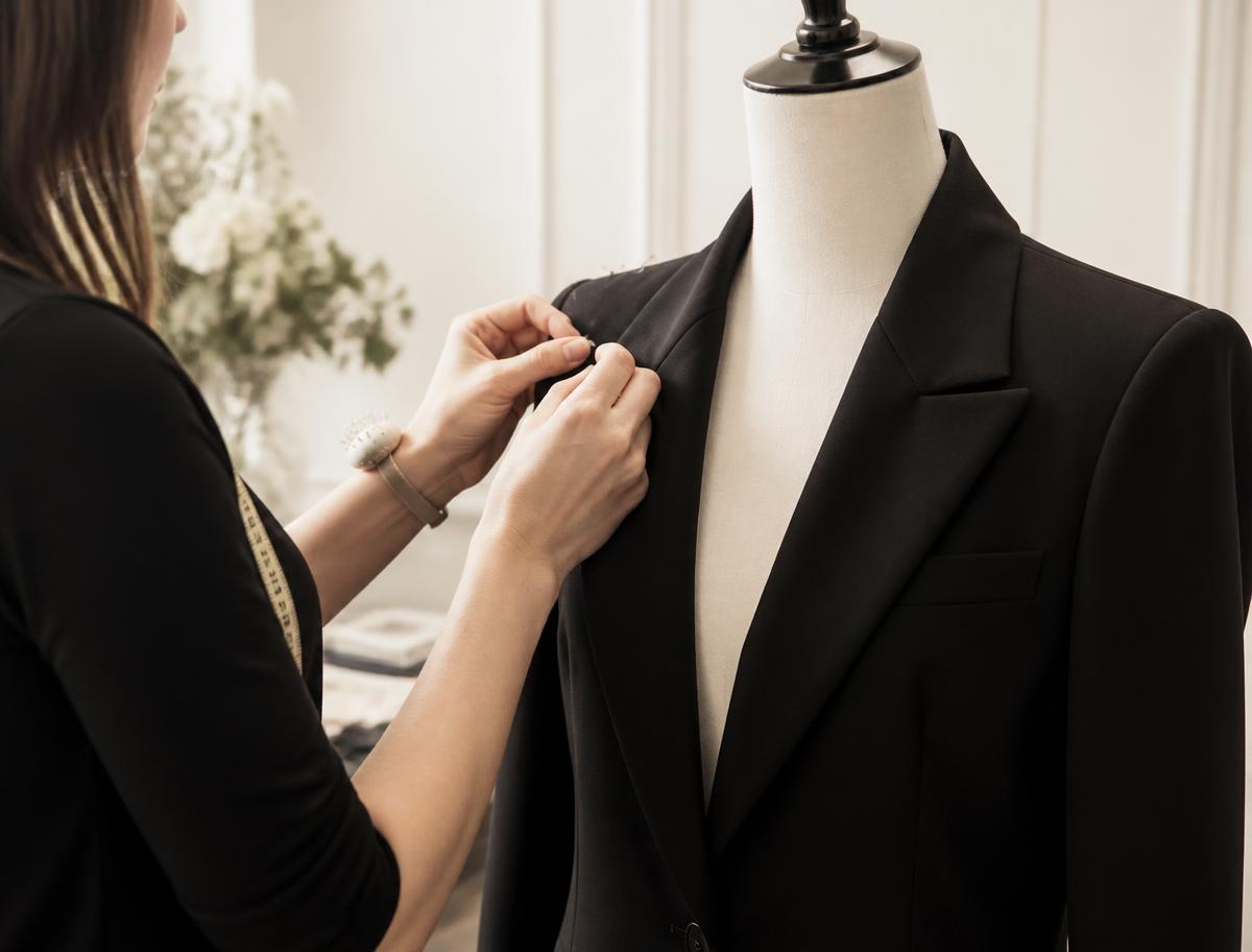 Tailor pinning the shoulder of a women's blazer on a dress form